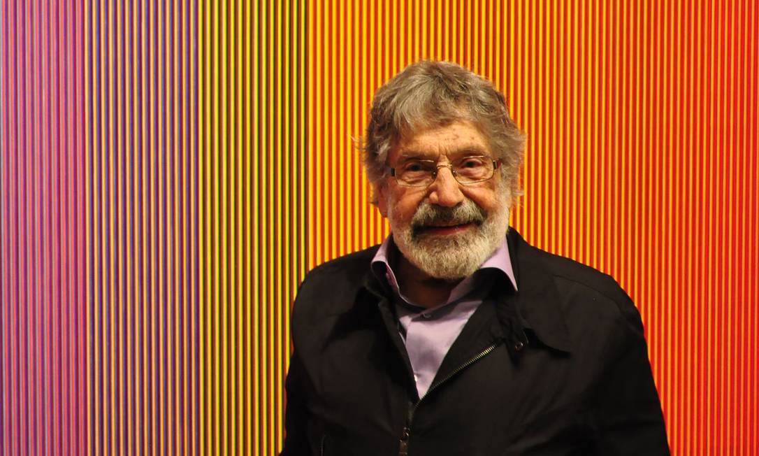 Imagem do artista Carlos Cruz-Diez frente a uma de suas obras.